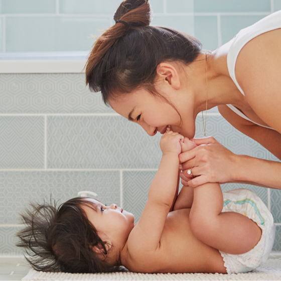 mother smiling down at her young baby on a changing table