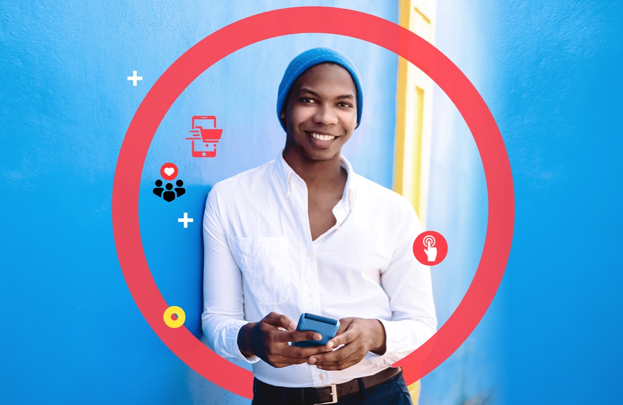 Woman leaning against the wall smiling and holding a phone